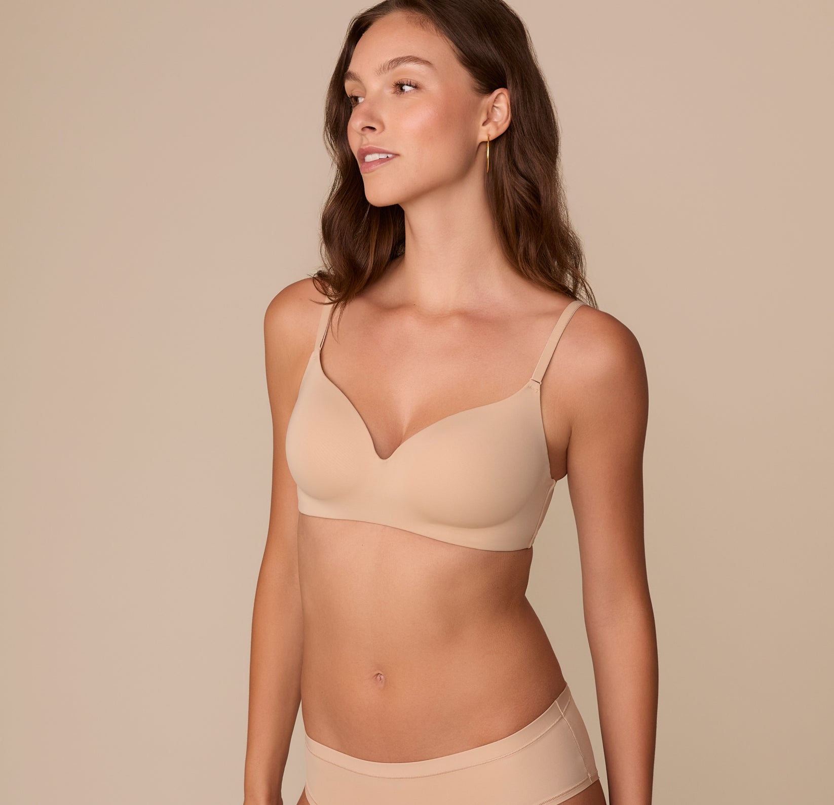 Three-quarter view of Alexis wearing the Base Wirefree T-Shirt Bra in Beige. The bra’s lightly lined cups and plunging neckline are visible, with microfiber fabric smoothing the silhouette.