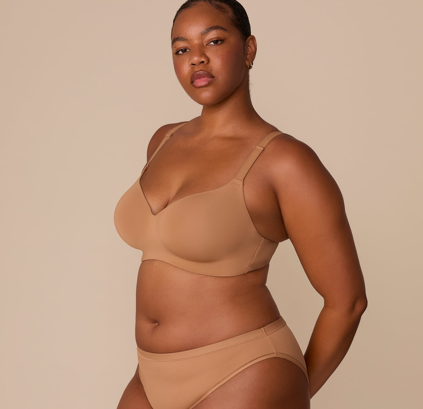 Three-quarter side view of Zarria in the Base Wirefree T-Shirt Bra and matching Bliss Bikini in Tan. The bra’s smooth cups and supportive band are visible.
