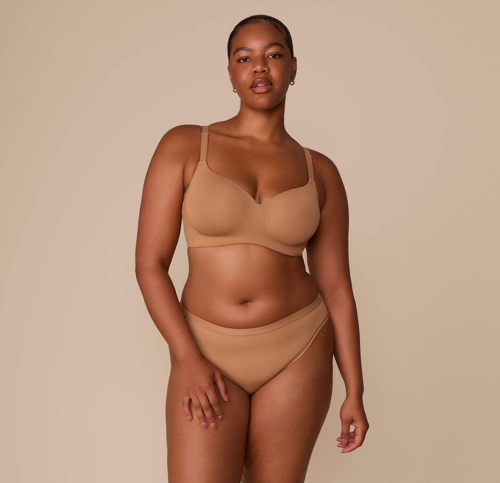 Full body shot of Zarria wearing the Base Wirefree T-Shirt Bra and Bliss Bikini in Tan. The image captures the set’s clean lines, supportive design, and stretch microfiber fabric.