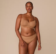Full body shot of Zarria wearing the Base Wirefree T-Shirt Bra and Bliss Bikini in Tan. The image captures the set’s clean lines, supportive design, and stretch microfiber fabric.