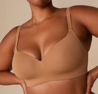 Close-up of Zarria wearing the Base Wirefree T-Shirt Bra in Tan. The image focuses on the plunge neckline and soft, lightly molded cups.