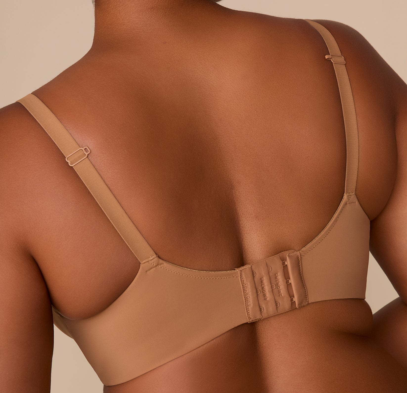 Close-up back view of Zarria wearing the Base Wirefree T-Shirt Bra in Tan. The image emphasizes the smooth back band and three-row hook-and-eye closure.
