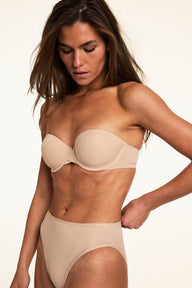 Against a soft studio backdrop, Gianna wears the Base Strapless Bra in Beige with matching underwear. The lightly lined strapless bra features smooth microfiber fabric, underwire support, and a straight neckline designed to stay in place.  