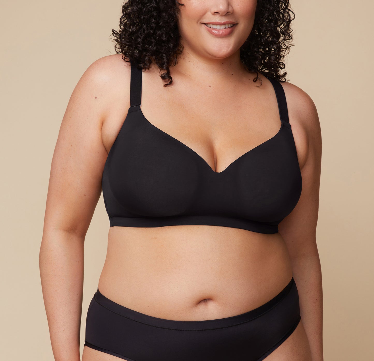 Bianca wears the Base Wirefree Bra in Black, showcasing its molded, lightly lined cups that provide natural shape without bulk. The adjustable straps are visible, emphasizing a customizable fit. sizing: Bianca wears size 38F