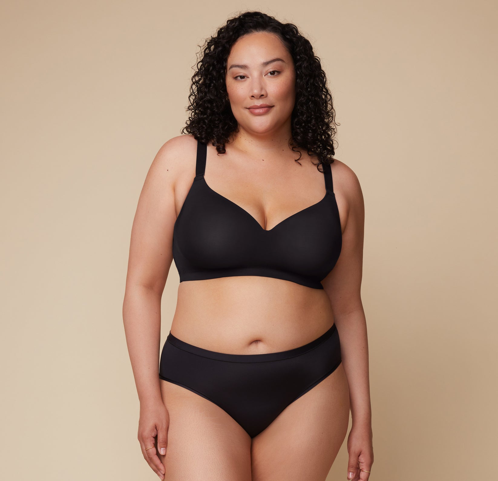 Bianca faces the camera wearing the Base Wirefree T-Shirt Bra in Black and the Bliss Hiphugger in the matching color.   