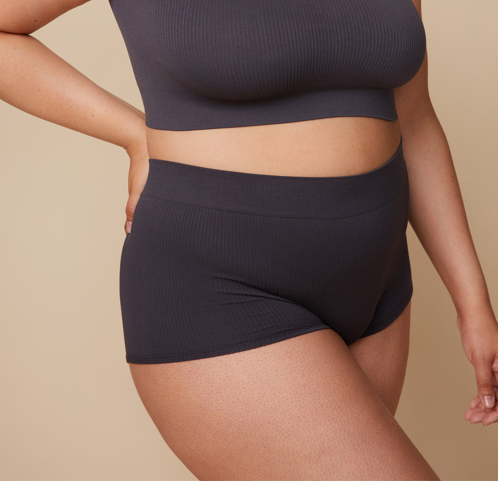 A side angle close-up focusing on Bianca’s midsection, highlighting the soft stretch and ribbed fabric of the Lounge Boyshort in Charcoal.