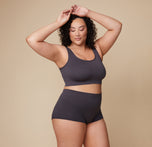 Bianca raises her arms, showcasing the side profile of the Lounge Rib Scoop Bralette and Lounge Rib Boyshort in Charcoal.