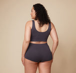 Bianca is turned to the side, showing the back of the Lounge Rib Scoop Bralette and Lounge Rib Boyshort in Charcoal. The seamless design offers full comfort and support.
