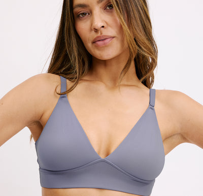 On a clean white backdrop, a model wears the Bliss Triangle Bralette in Steel, shown in a close-up that highlights the deep V neckline, smooth microfiber fabric, and thin adjustable straps for soft, wireless comfort.