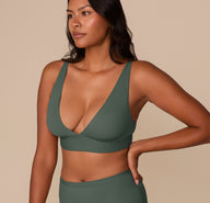 Side angle of Victoria modeling the Bliss Plunge Adjustable Bralette in Fir with plunging neckline detail.