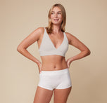 Megan smiling and wearing the Bliss Plunge Adjustable Bralette in Frost paired with the Lounge Rib Boyshort in White. The image showcases the bralette’s wireless comfort and sleek, everyday wearability.