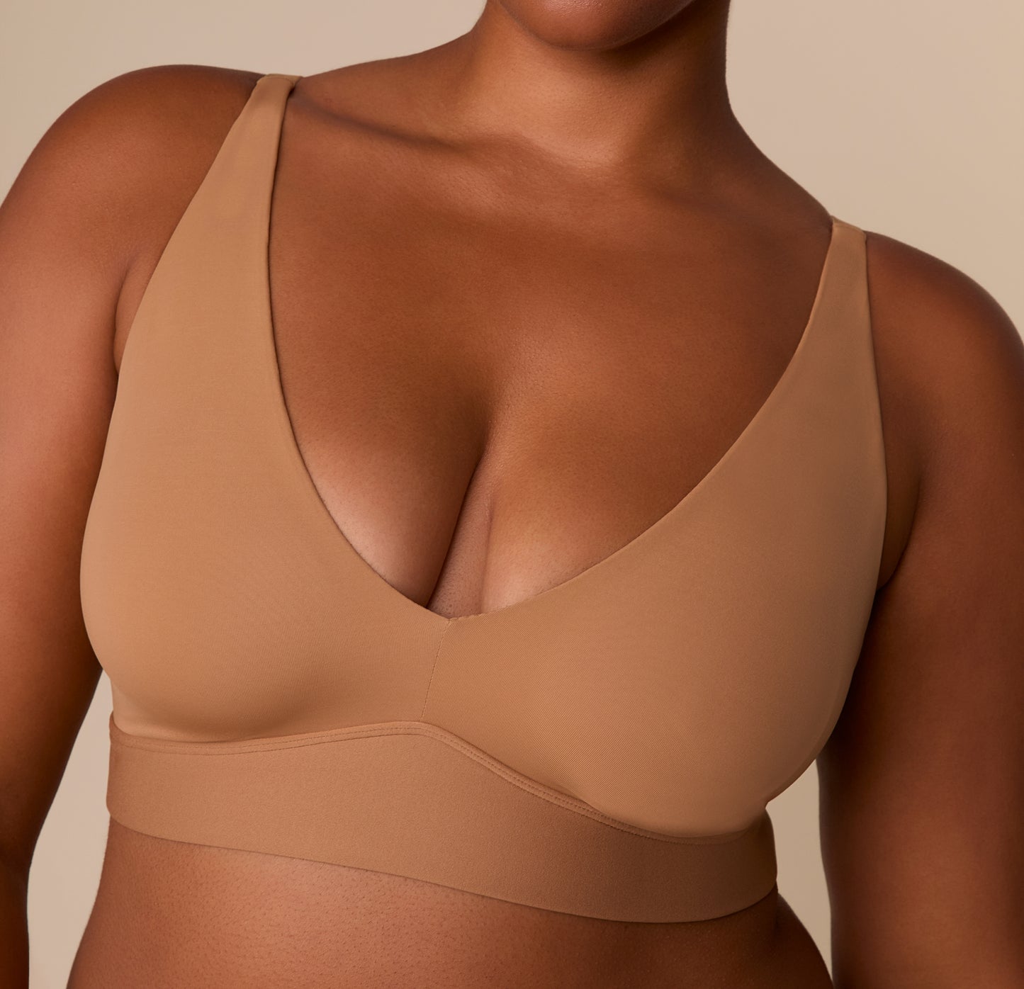 Zoomed-in front detail of the Bliss Plunge Adjustable Bralette in Tan, emphasizing the seamless cups and fabric texture.