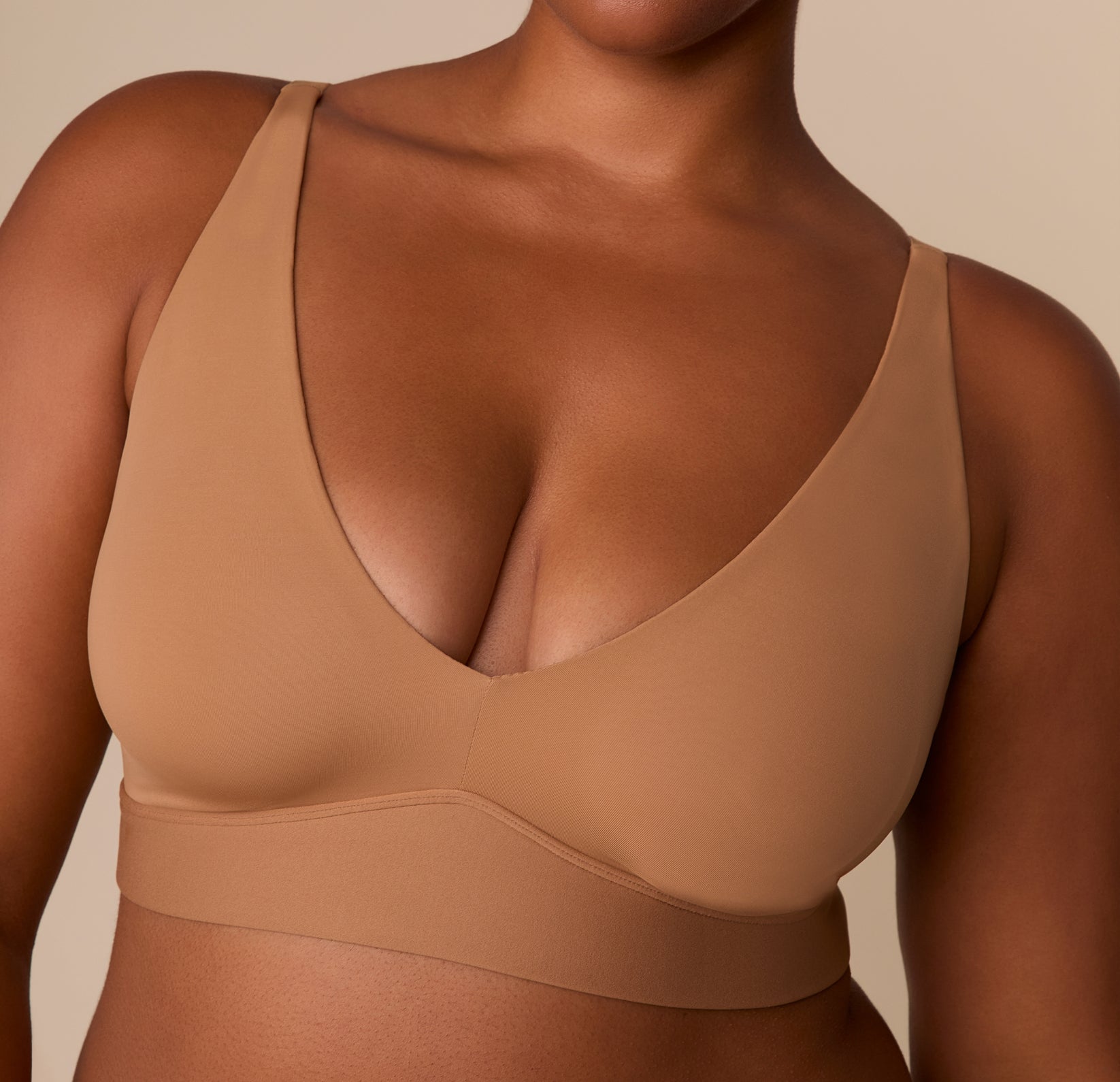 Zoomed-in front detail of the Bliss Plunge Adjustable Bralette in Tan, emphasizing the seamless cups and fabric texture.