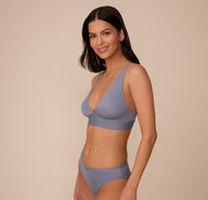 Three-quarter front view of Marcela in the Bliss Plunge Adjustable Bralette and matching Bliss Bikini in Steel. The pose emphasizes the plunge neckline and minimal, smooth lines of the set.