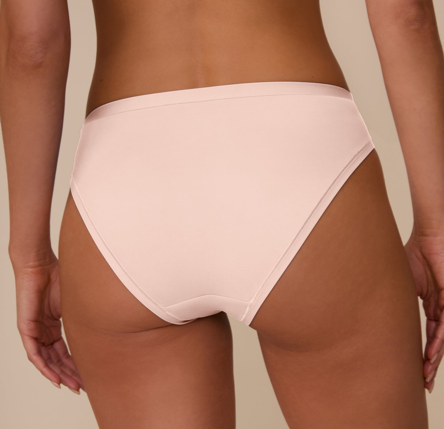 Rear close-up of Marcela wearing the Bliss Bikini in Rose. The image emphasizes the smooth, no-show finish and soft fabric along the waistband and leg openings.