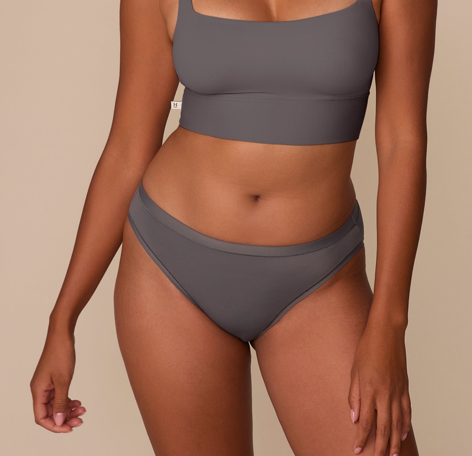 Victoria wearing the Bliss Bikini in Smoke. The bikini features a mid-rise silhouette and no elastic at the waist or legs for a smooth, dig-free fit. sizing: Victoria wears size Medium