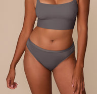 Victoria wearing the Bliss Bikini in Smoke. The bikini features a mid-rise silhouette and no elastic at the waist or legs for a smooth, dig-free fit. sizing: Victoria wears size Medium