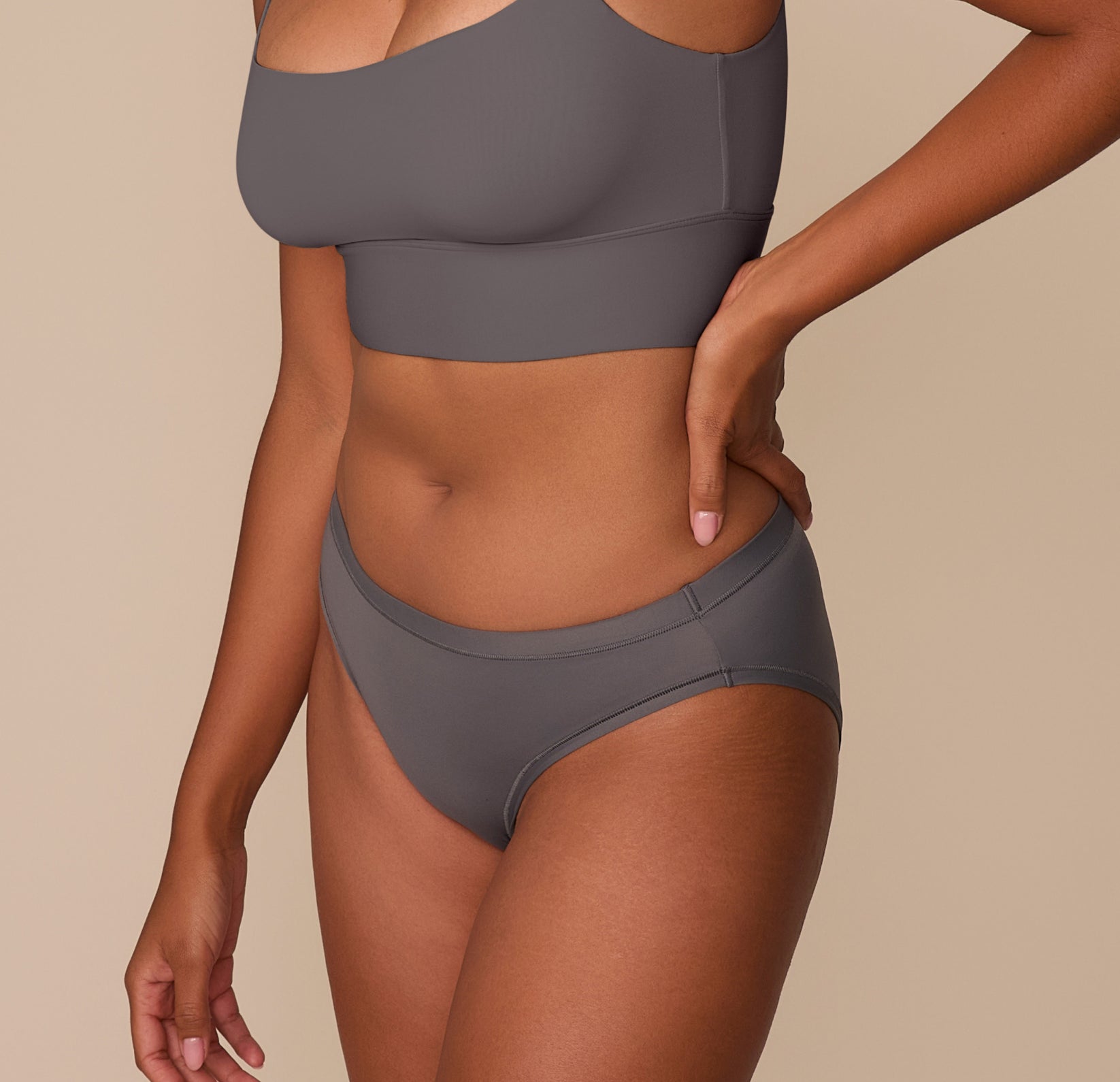Side view of Victoria modeling the Bliss Bikini in Smoke, emphasizing the minimal seams and soft stretch of the fabric.