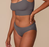 Side view of Victoria modeling the Bliss Bikini in Smoke, emphasizing the minimal seams and soft stretch of the fabric.