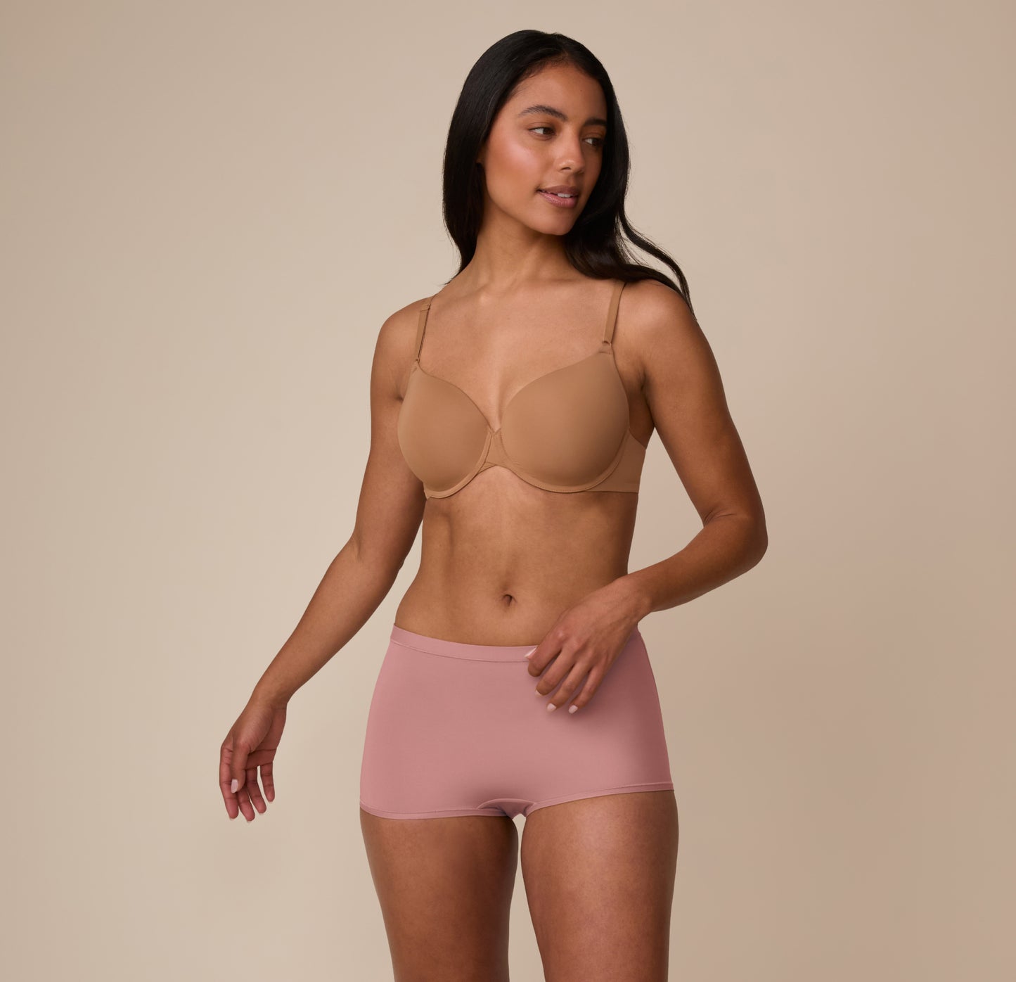 Full body shot of Marcela wearing the Bliss Boyshort in Plum with a beige bra. The boyshort emphasizes a smooth, no-dig fit with breathable softness.