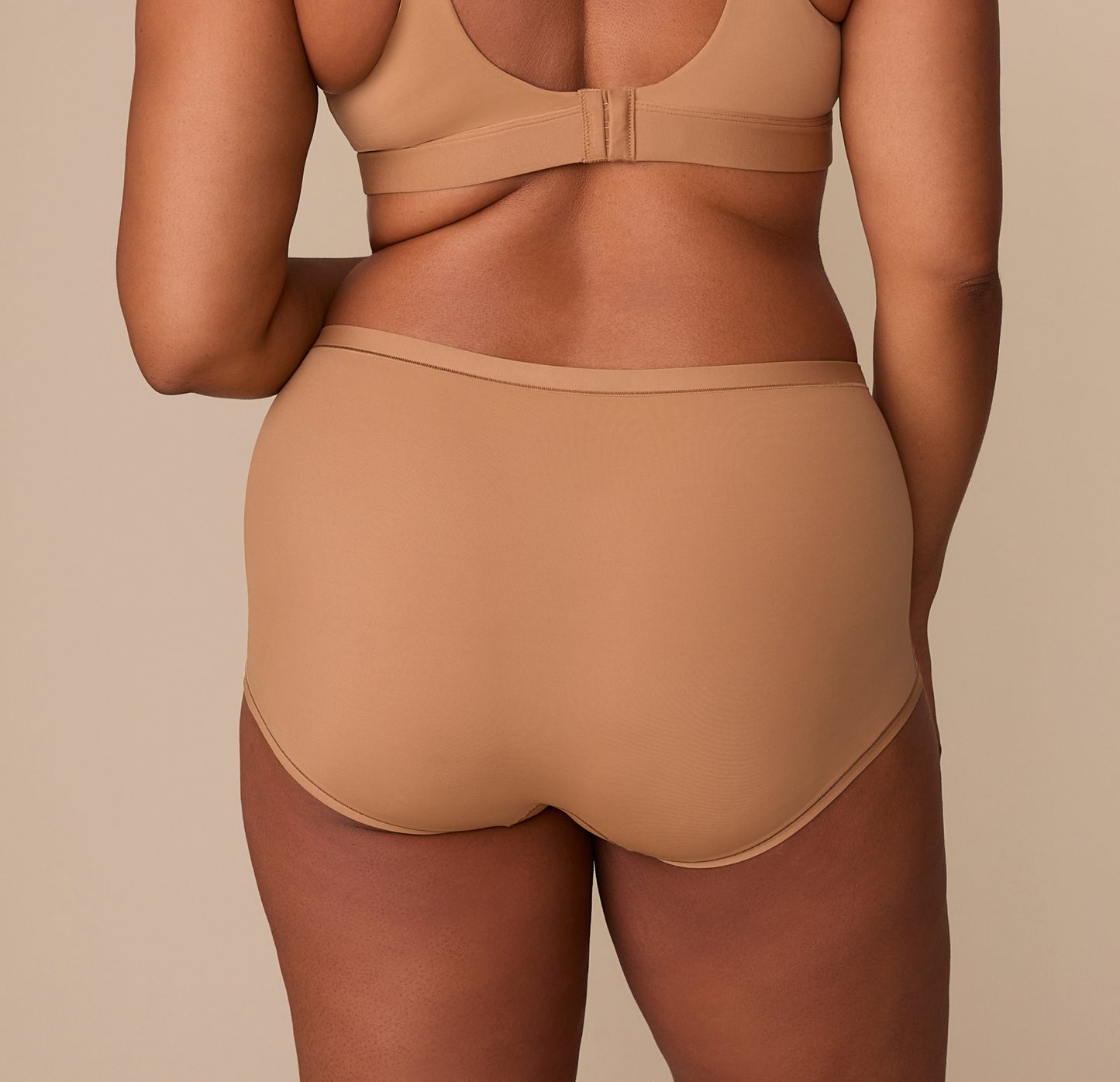 Back view of Zarria in the Bliss Boyshort in Tan, showing the wide waistband and soft, stretchy fabric that hugs the body without digging in.