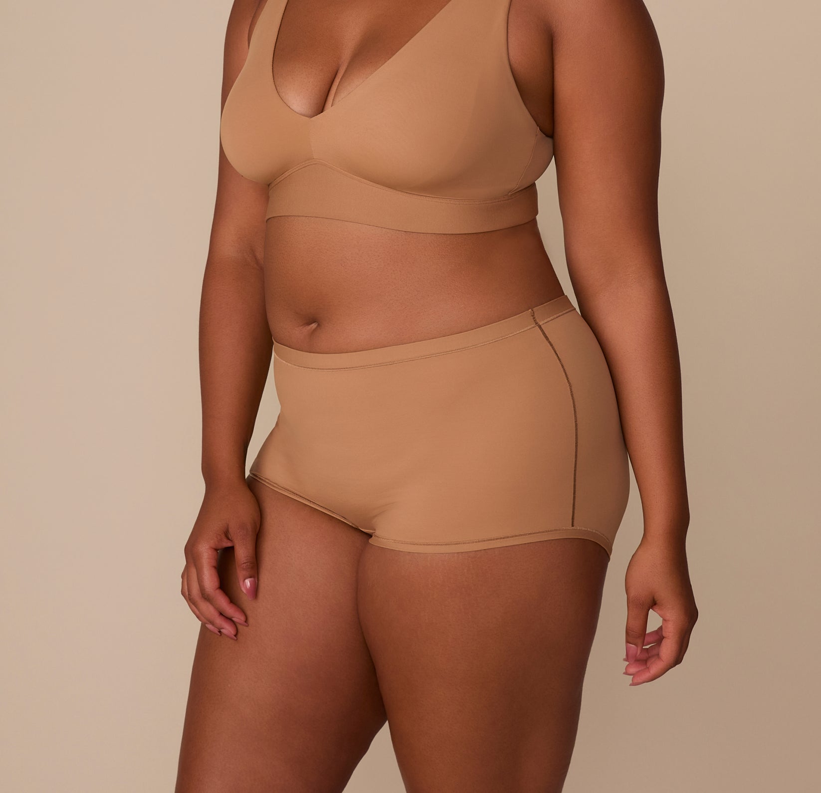 Three-quarter angle of Zarria in the Bliss Boyshort in Tan, showing the smooth side panel and flat leg openings for no-show wear.