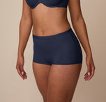 Three quarter angle of Nemesis modeling the Bliss Boyshort in True Blue, capturing the barely-there seams and buttery-soft finish.