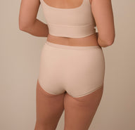 A rear view of Sonnie modeling the Bliss Boyshort in Beige, showcasing the smooth, no-dig waistband and full-coverage design that provides a secure, stay-put fit.