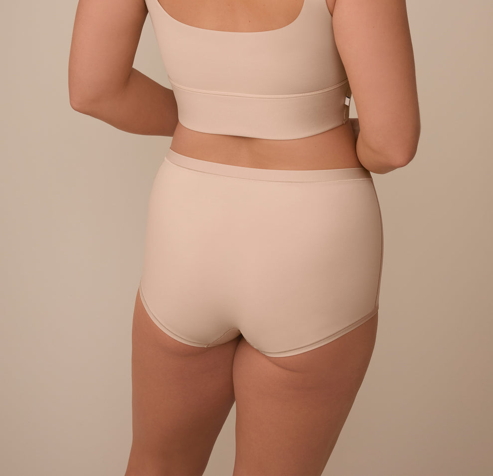 A rear view of Sonnie modeling the Bliss Boyshort in Beige, showcasing the smooth, no-dig waistband and full-coverage design that provides a secure, stay-put fit.