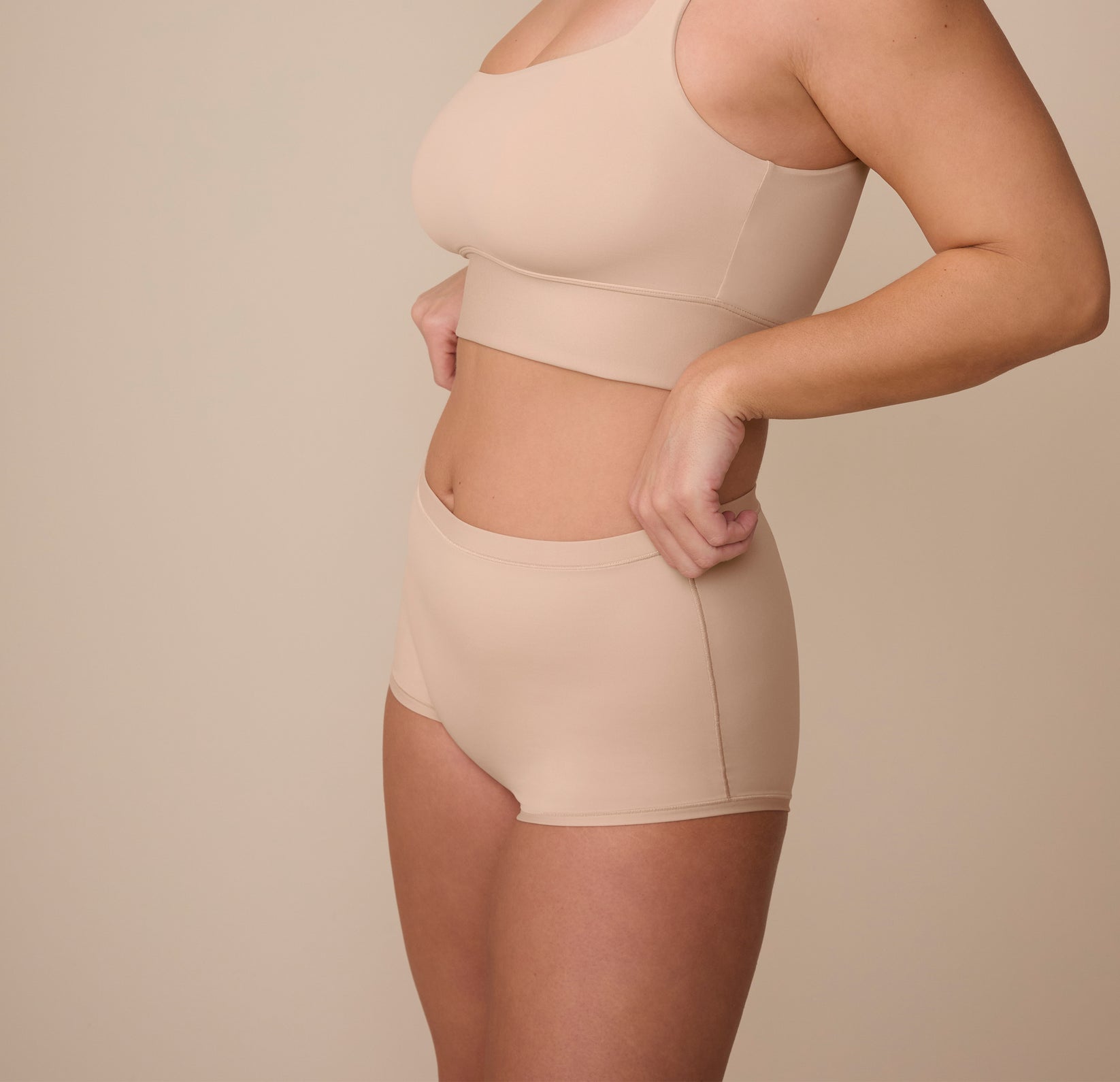 Sonnie wearing the Bliss Boyshort in Beige, captured from a side profile to highlight the soft stretch fabric and curve-hugging fit.