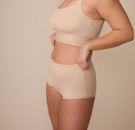 Sonnie wearing the Bliss Boyshort in Beige, captured from a side profile to highlight the soft stretch fabric and curve-hugging fit.