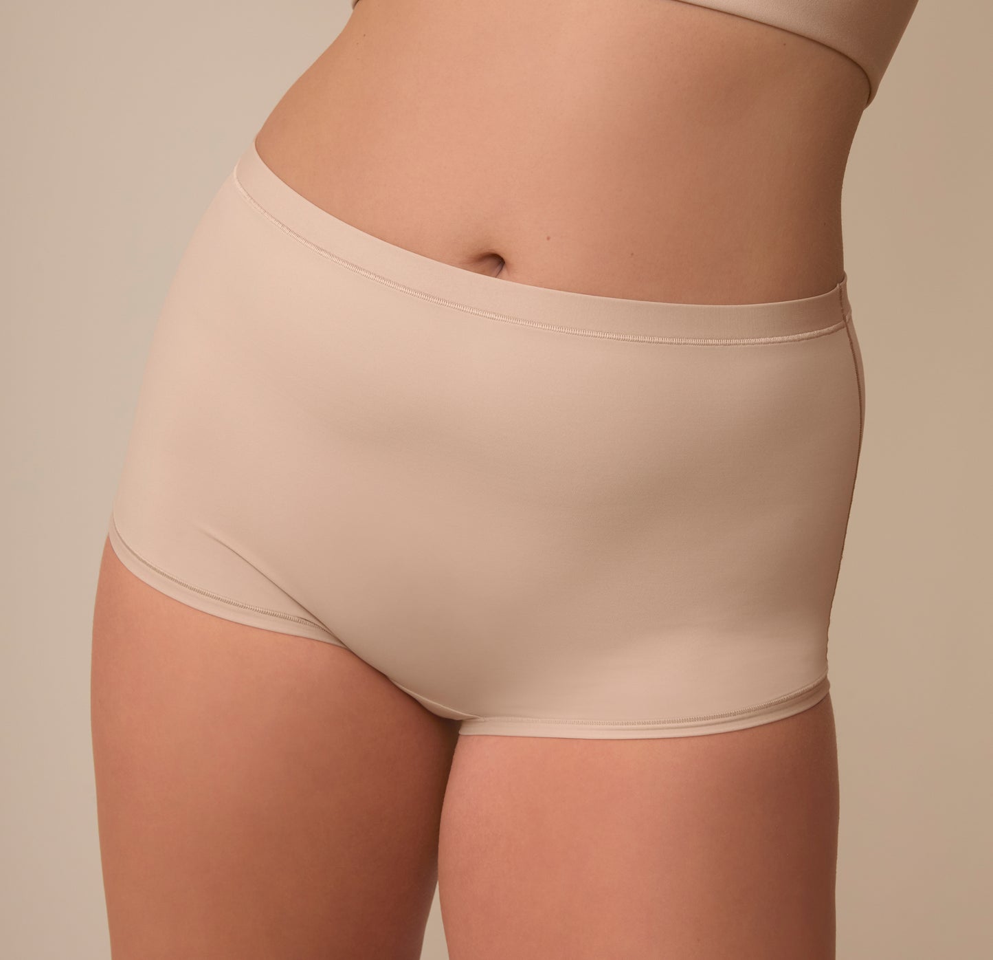 A close-up of Sonnie wearing the Bliss Boyshort in Beige, focusing on the smooth fabric and minimal seams construction designed for an invisible look under clothing.