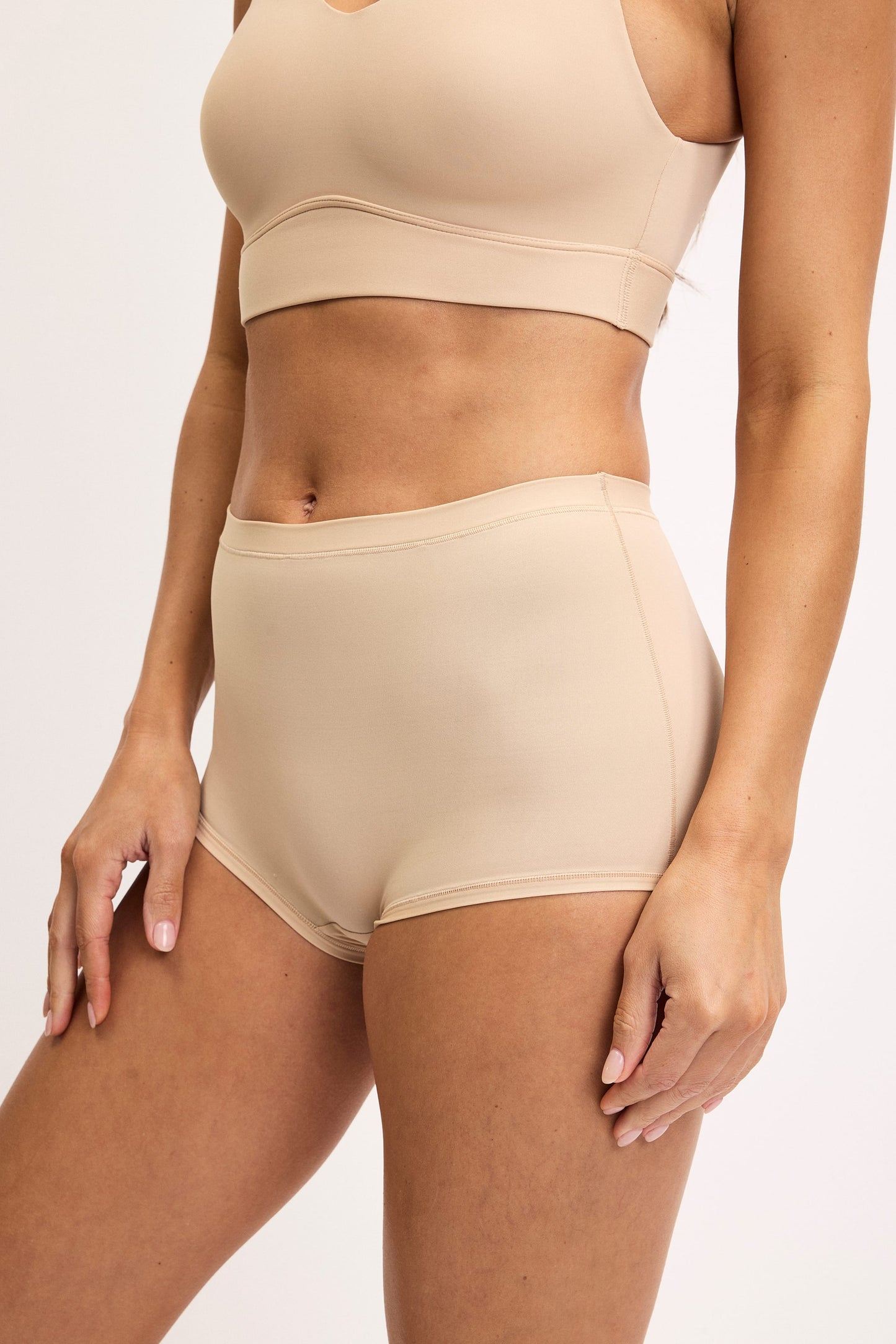 Darion wears the Bliss Boyshort in Beige with the Bliss Scoop Bralette, highlighting the high-rise silhouette and smooth microfiber fabric.