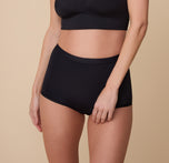 A close-up of model Gracie wearing the Bliss Boyshort in Black. The high-rise, full-coverage fit offers a smooth look and comfortable feel. sizing: Gracie wears size Small
