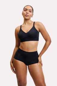On a clean studio backdrop, Amber wears the Bliss Boyshort in Black with a matching Bliss Bralette. The boyshort sits at the natural waist with a smooth waistband, soft microfiber fabric, and full back coverage.
