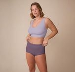 Sonnie poses in a relaxed, full-body view wearing the Bliss Boyshort in Eclipse and the Bliss Bralette in Violet. The set showcases a sleek, comfortable fit with smooth lines and soft-touch fabric.