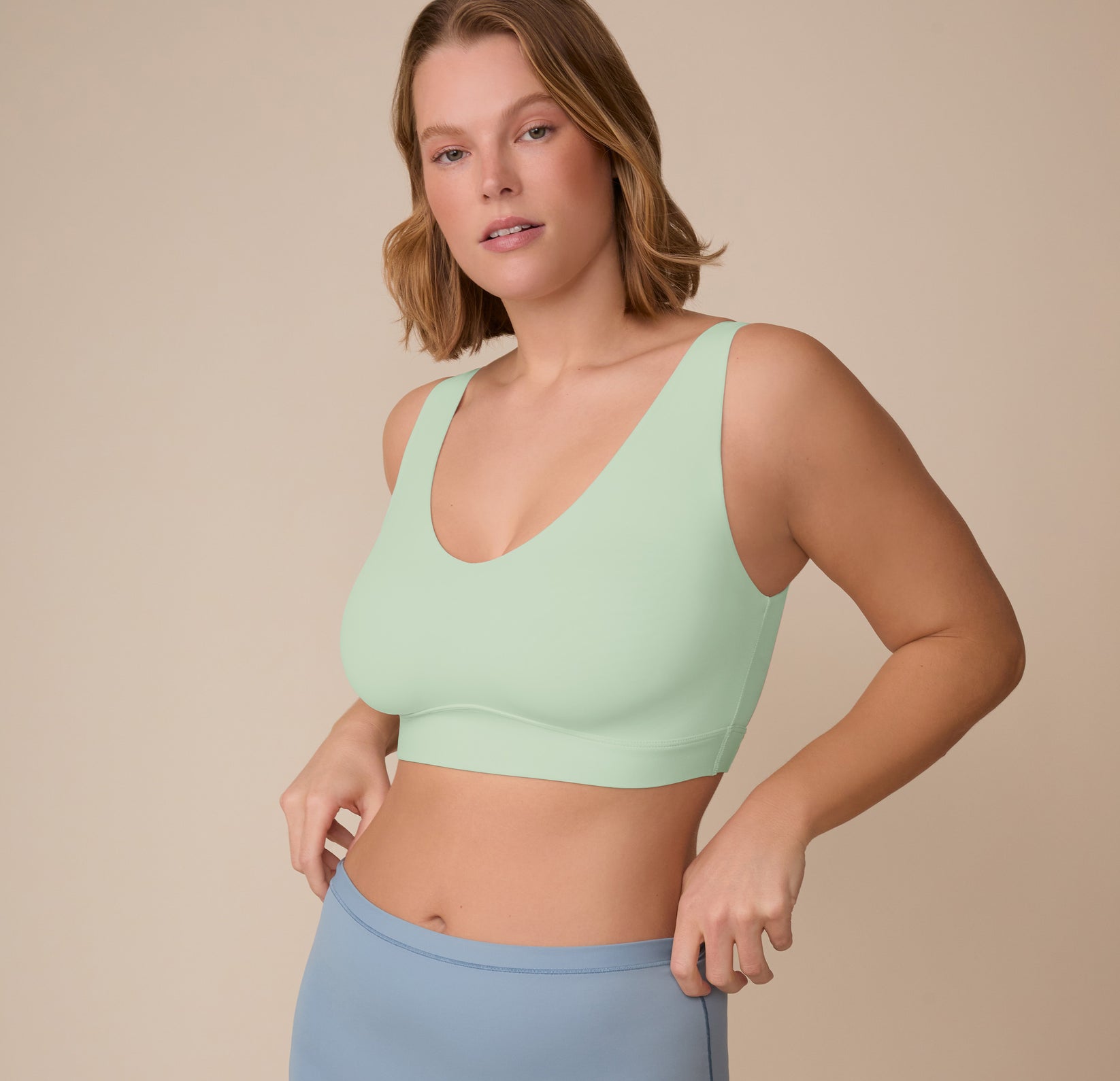 Three-quarter angle of Sonnie adjusting the waistband of the Bliss Boyshort in Glacier while wearing the Bliss Bralette in Dew, showcasing the everyday comfort and flexible fit.