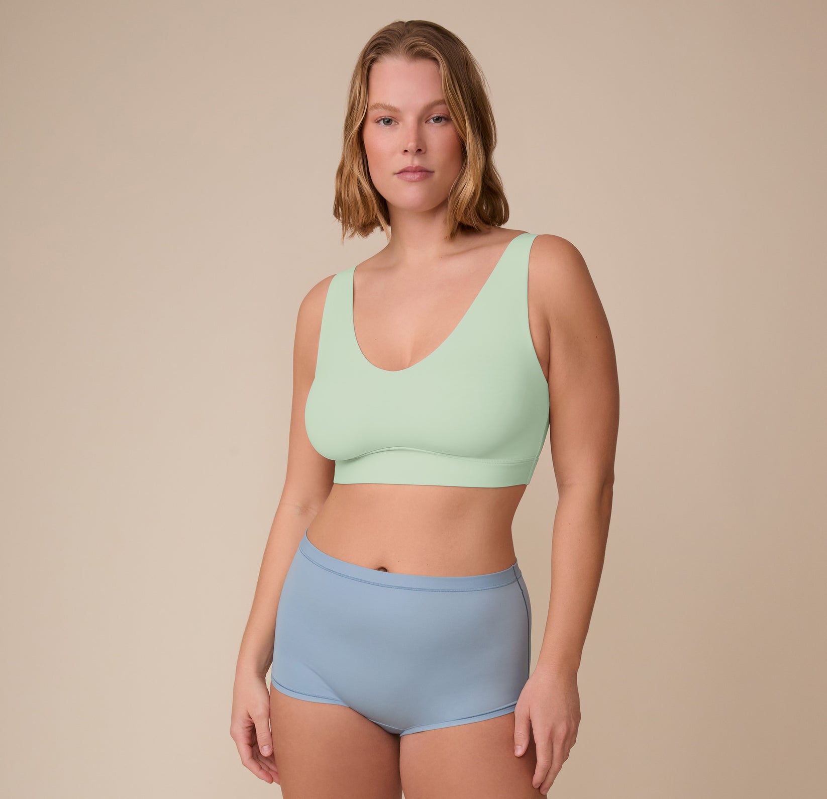 Full body view of Sonnie wearing the Bliss Bralette in Dew and the Bliss Boyshort in Glacier.The bralette’s wide straps and supportive band are clearly visible.