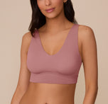 Marcela wearing the Bliss Bralette in Plum, facing forward. The image highlights the deep V-neckline and wide wireless band of the ultra-soft bralette. sizing: Marcela wears size Small