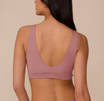 Back view of Marcela wearing the Bliss Bralette in Plum, showcasing the wide shoulder straps and smooth, deep scoop back design.
