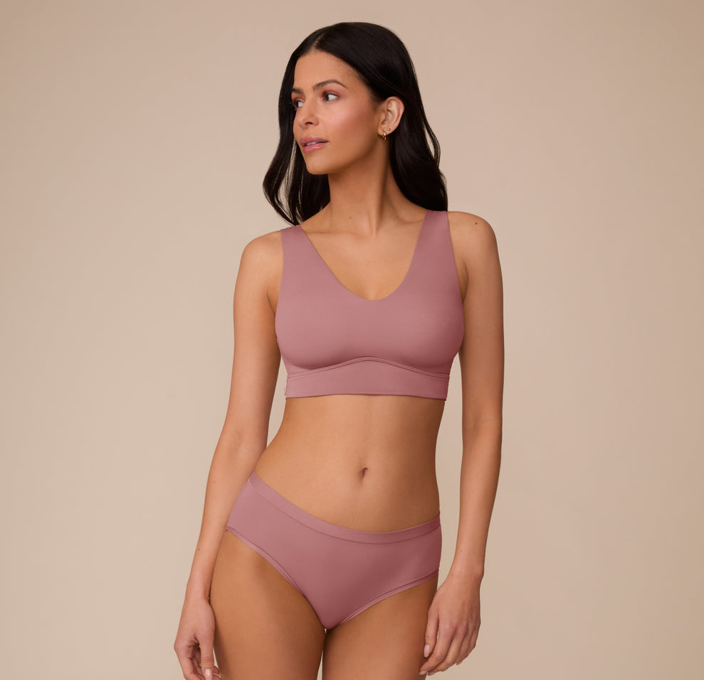 Full-body shot of Marcela wearing the Bliss Bralette and matching Bliss Highwaist Brief in Plum. The image displays the complete set, emphasizing the soft fabric and comfortable fit.