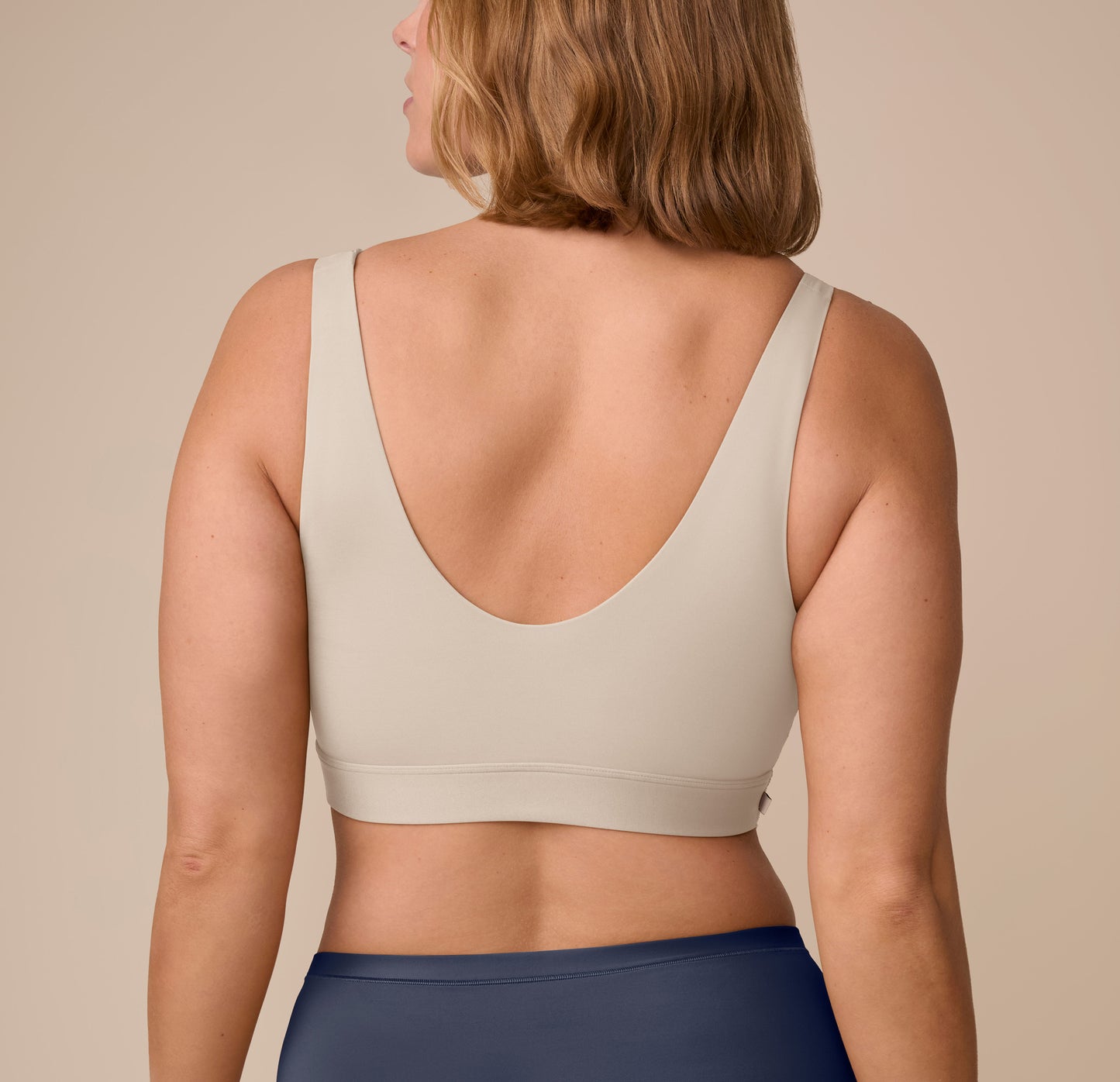Back view of Sonnie in the Bliss Bralette in Sand, highlighting the deep scoop back and soft, stretchy band for a barely-there feel.