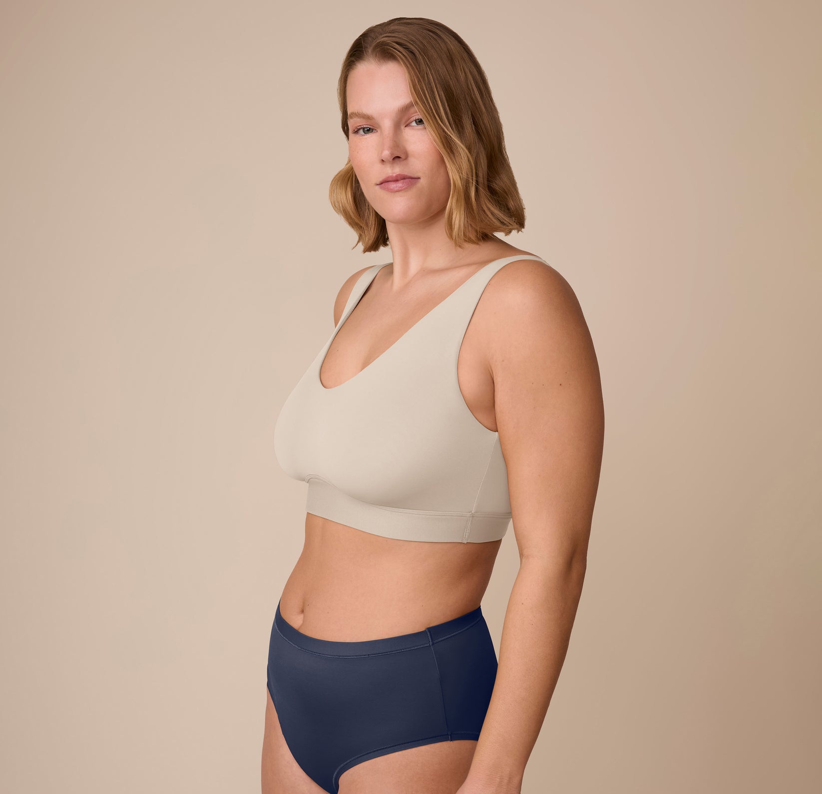 Side angle of Sonnie modeling the Bliss Bralette in Sand paired with the Bliss Highwaist Brief in True Blue. The image highlights the wireless, second-skin fit.