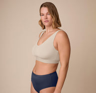 Side angle of Sonnie modeling the Bliss Bralette in Sand paired with the Bliss Highwaist Brief in True Blue. The image highlights the wireless, second-skin fit.