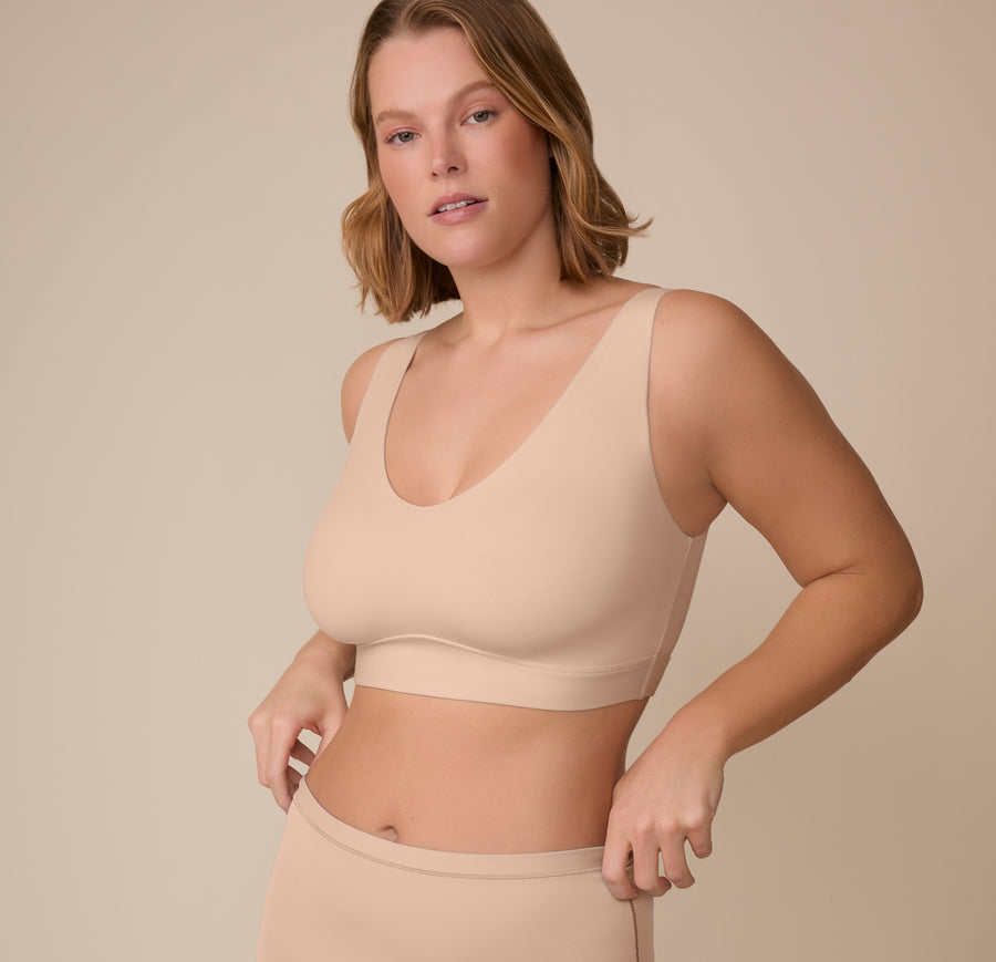 Three-quarter angle of Victoria wearing the Bliss Bralette in Beige. Her relaxed stance highlights the natural shaping and comfort-first construction.