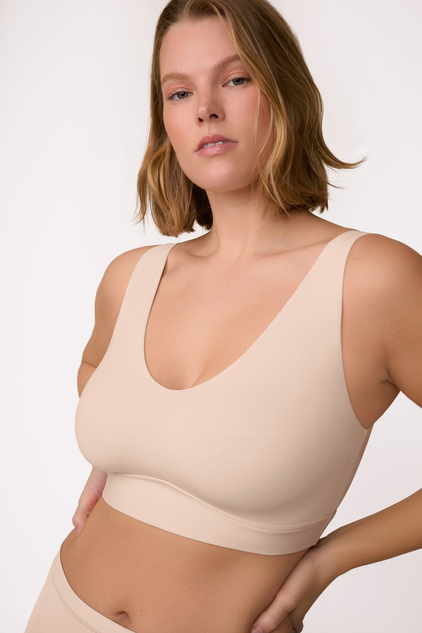 On a light neutral studio backdrop, Sonny wears the Bliss Bralette in Beige, shown from the front. The wireless design features a scoop neckline, smoothing sides, and ultra-soft microfiber fabric for everyday comfort. sizing: Sonnie wears size XL
