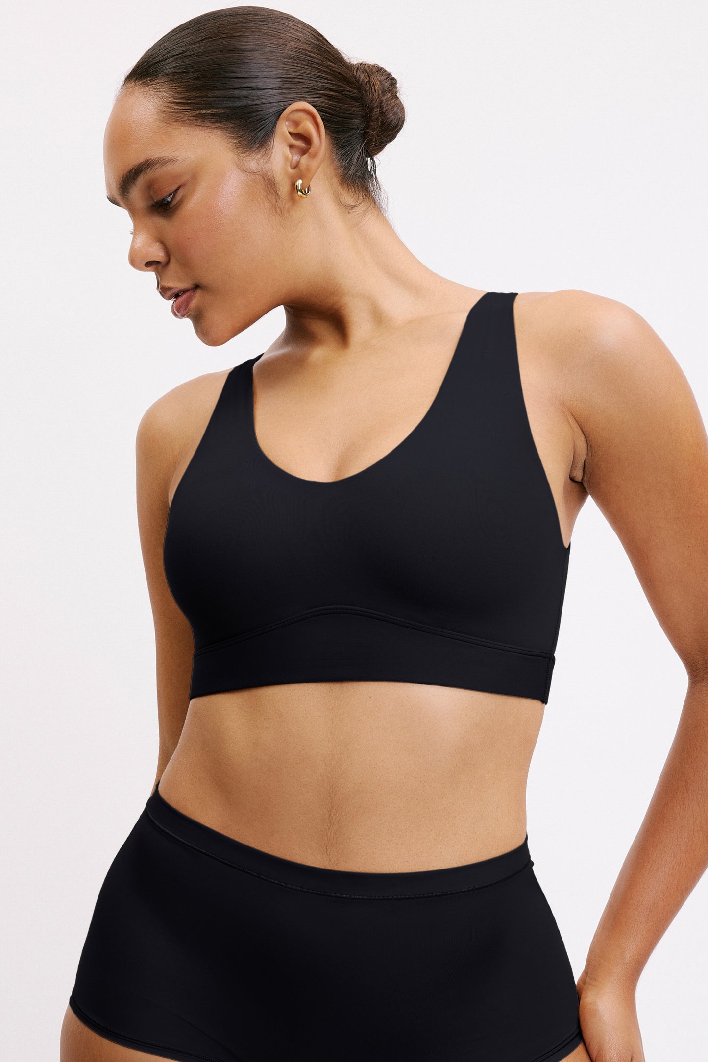 On a light neutral studio backdrop, Amber wears the Bliss Bralette in Black with matching underwear, shown from the front. The pullover style and ultra-soft microfiber fabric create a smooth, everyday fit. sizing: Amber wears size Medium