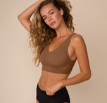 Side angle of Freya wearing the Bliss Bralette in Brown. Her arm is raised, showing off the clean construction and second-skin fabric.