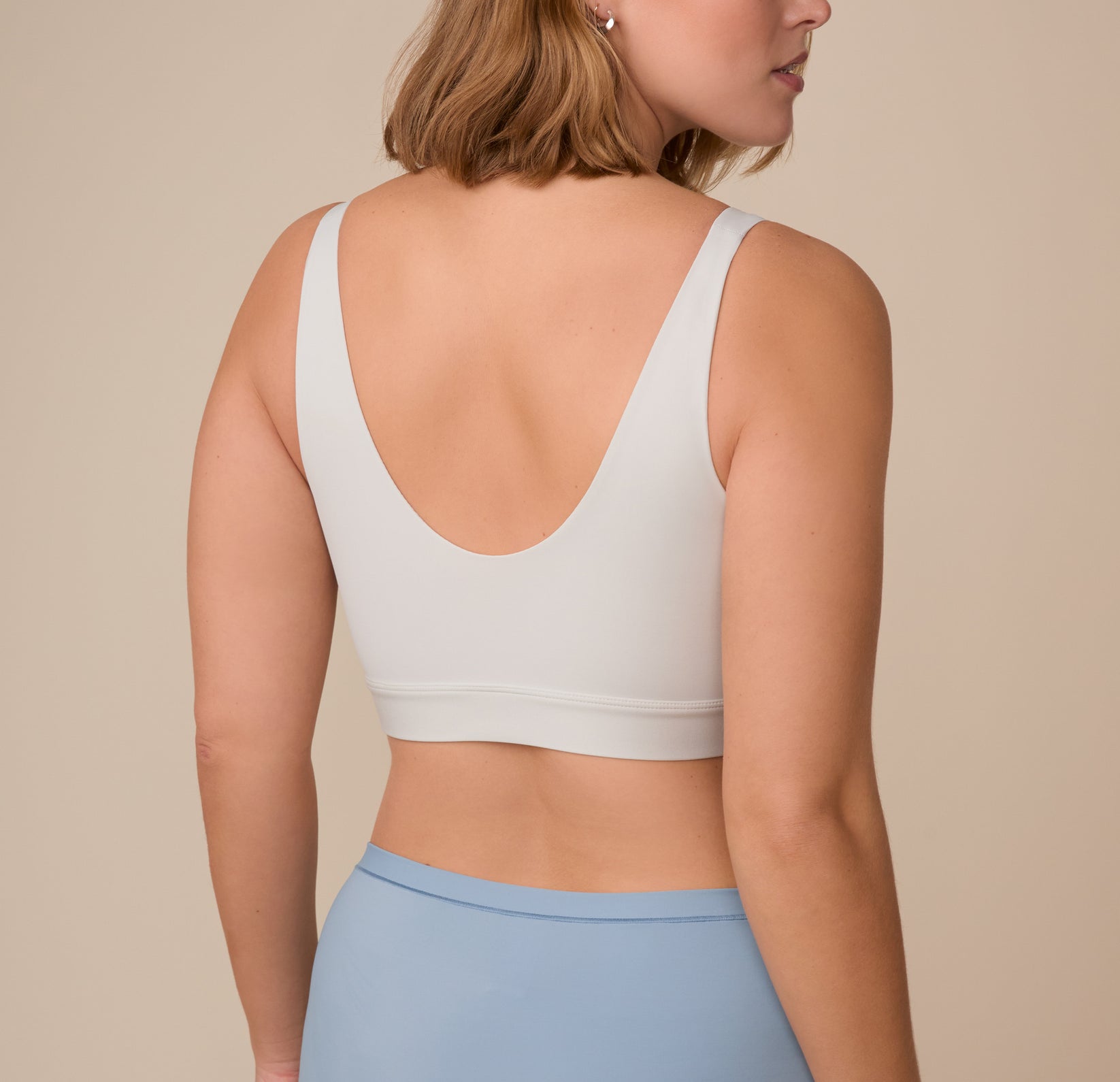 Back view of Sonnie in the Bliss Bralette in Frost. The wide, comfortable straps and scoop back are shown clearly, highlighting the bralette’s minimal seams and ultra-soft finish.