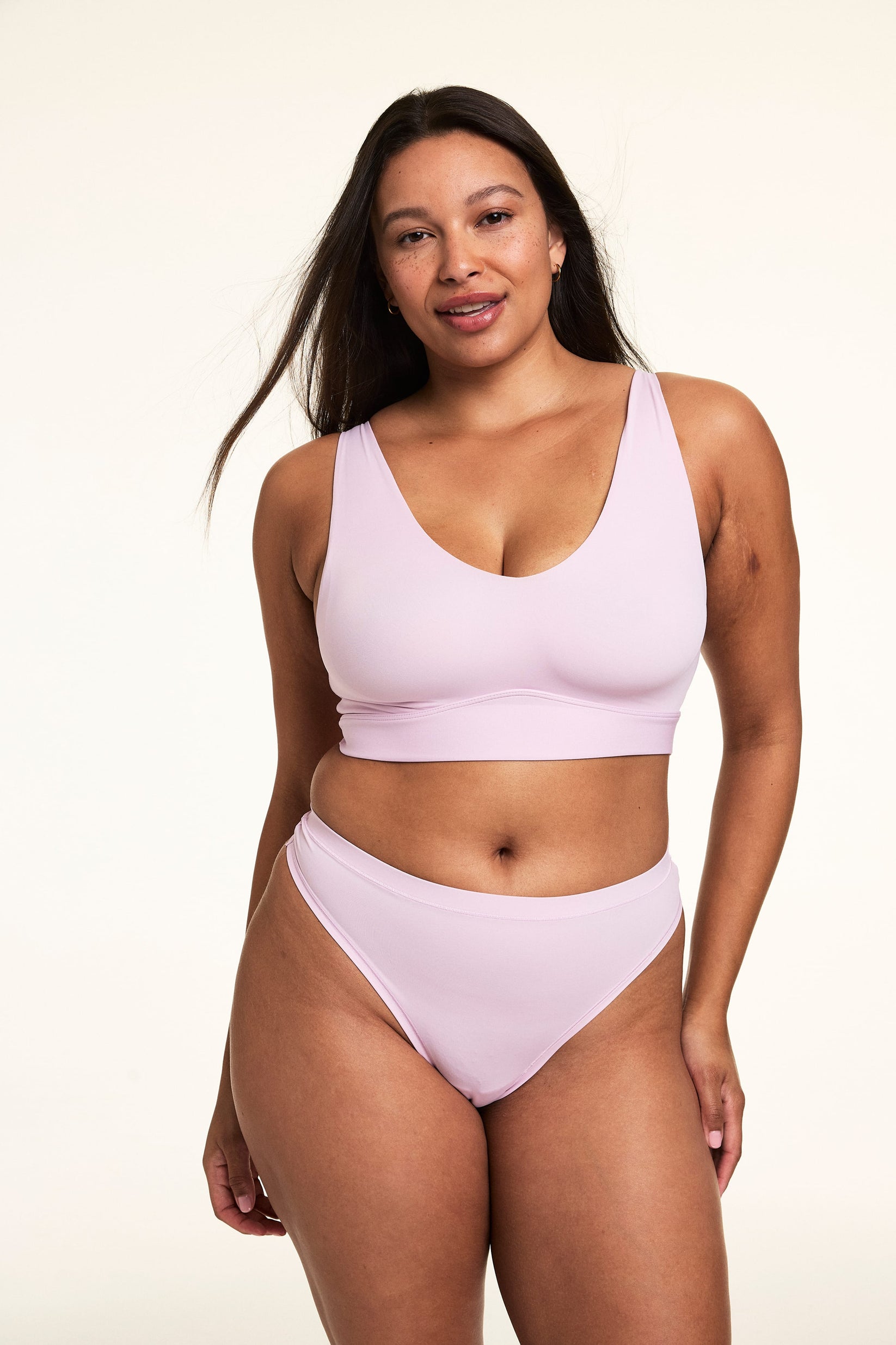 On a light studio backdrop, Alana wears the Bliss Bralette in Retro Lilac with matching underwear. The wireless bralette features a scoop neckline, smoothing sides, and soft microfiber fabric. 